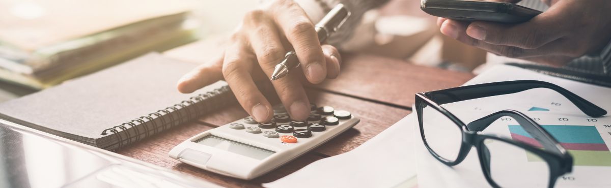 A person's hand using a calculator on a desk A person's hand using a calculator on a desk